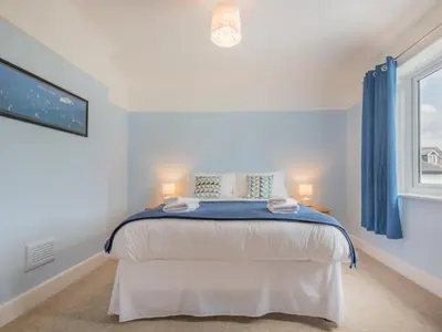 a bedroom with a bed with blue curtains and a window at 3 Bed in Keswick oc-sz283 in Keswick