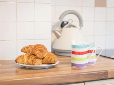 a plate of croissants on a counter next to a coffee mug at 2 Bed in Glenridding SZ178 in Glenridding