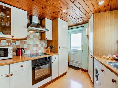 a kitchen with white cabinets and a wooden ceiling at 2 Bed in Keswick oc-sz145 in Braithwaite