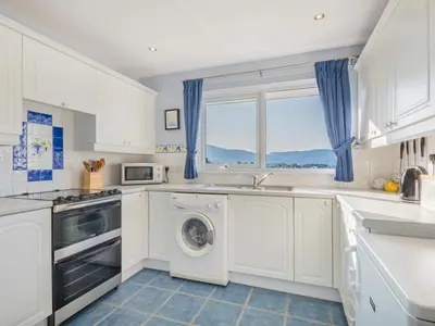 a white kitchen with a washing machine and a window at 1 Bed in Keswick oc-sz437 in Keswick