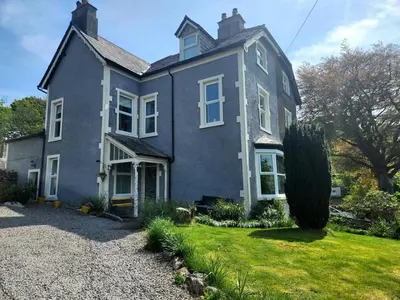 a large blue house with a grass yard at 2 Bed in Holmrook oc-sz464 in Beckfoot