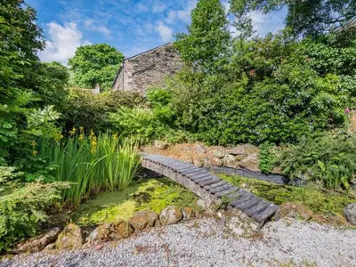a stone bridge over a pond in a garden at 2 Bed in Penrith oc-sz218 in Mosedale