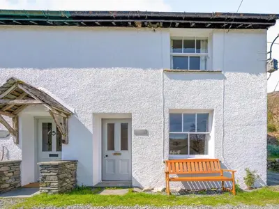 a white cottage with a bench in front of it at 3 Bed in Borrowdale SZ234 in Rosthwaite