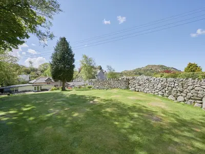 a yard with a stone wall and a tree at 1 Bed in Eskdale SZ471 in Beckfoot