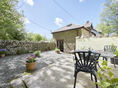 a patio with a table and chairs and a stone wall at 1 Bed in Eskdale SZ471 in Beckfoot