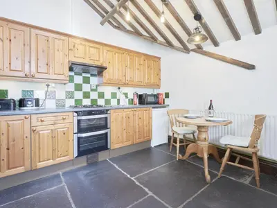 a kitchen with wooden cabinets and a table with chairs at 1 Bed in Eskdale SZ471 in Beckfoot