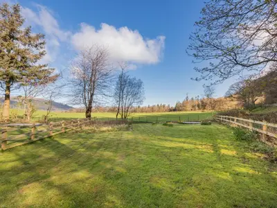 a field with a fence and trees in the background at 2 Bed in Keswick oc-sz199 in Applethwaite