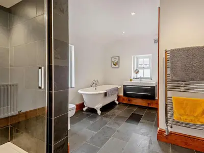 a bathroom with a tub and a shower and a sink at 4 Bed in Cockermouth oc-sz037 in Cockermouth