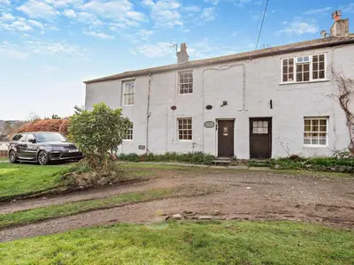 a car parked in front of a white house at 3 Bed in Braithwaite SZ174 in Braithwaite