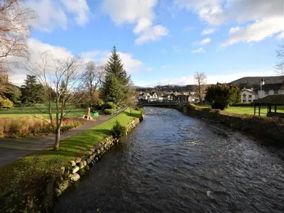 a river with a stone wall next to a street at 2 Bed in Keswick 86001 in Keswick