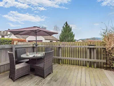 a patio with a table and an umbrella on a fence at 2 Bed in Keswick 86001 in Keswick