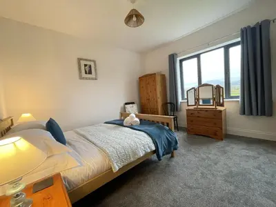a bedroom with a bed and a large window at Langrigg Cottage HOT TUB HIRE AVAILABLE in Portinscale