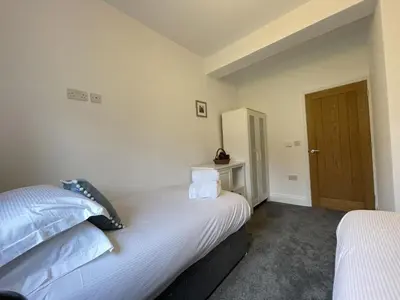 two beds in a room with a door at Langrigg Cottage HOT TUB HIRE AVAILABLE in Portinscale