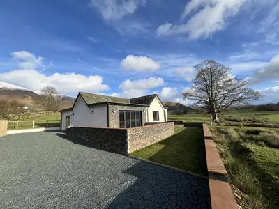 a house sitting on the side of a road at Langrigg Cottage HOT TUB HIRE AVAILABLE in Portinscale
