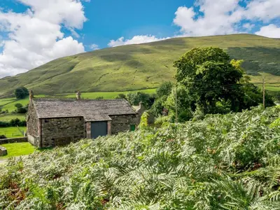 an old stone house on a hill with a green mountain at 1 Bed in Penrith oc-88201 in Mosedale