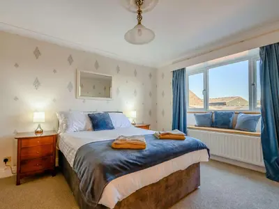 a bedroom with a bed and a window with blue curtains at 3 Bed in Aspatria 89139 in Aspatria