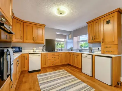 a large kitchen with wooden cabinets and white appliances at 3 Bed in Aspatria 89139 in Aspatria