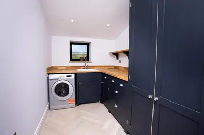 a laundry room with a washing machine and a sink at Sheepfold Barn in Penruddock