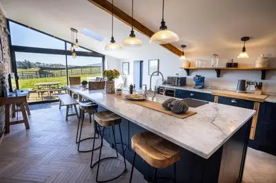 a kitchen with a large counter and a large window at Sheepfold Barn in Penruddock