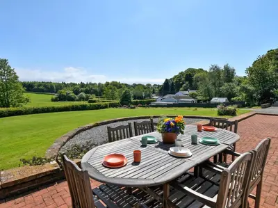 a wooden table with chairs and flowers on a patio at 3 Bed in Dovenby 90920 in Tallentire