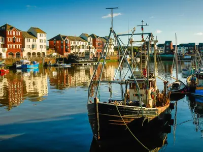 a boat is docked in a harbor with houses at 3 Bed in Dovenby 90920 in Tallentire