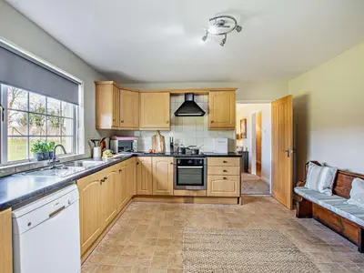 a kitchen with wooden cabinets and a sink and a window at 3 Bed in Dovenby 90920 in Tallentire