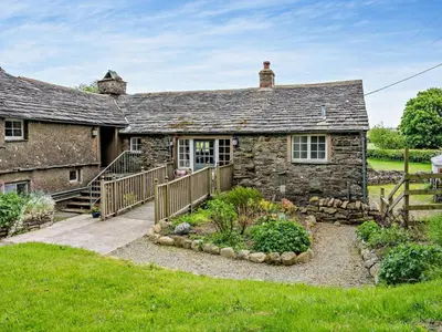 an old stone house with a wooden walkway in front of it at 1 Bed in Mosedale 91232 in Mosedale