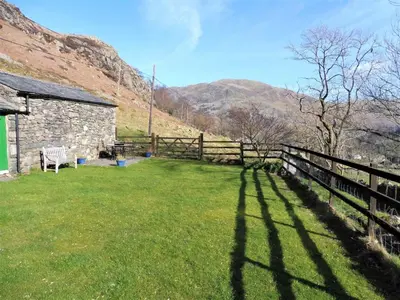a fence and a bench in a yard with mountains at 2 Bed in Glenridding 90874 in Glenridding