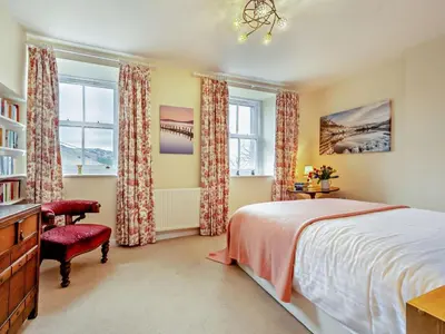 a bedroom with a bed and a chair and windows at 1 Bed in Penrith oc-91812 in Dockray