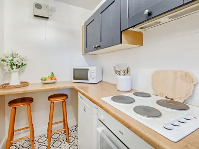 a kitchen with a stove and a counter with stools at 2 Bed in Keswick 91901 in Keswick