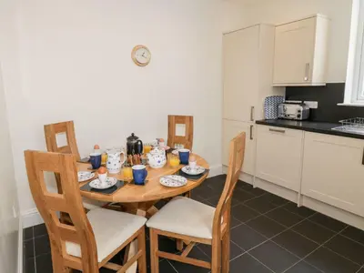 a kitchen with a wooden table and chairs in a room at Haven Cottage in Kirkcudbright