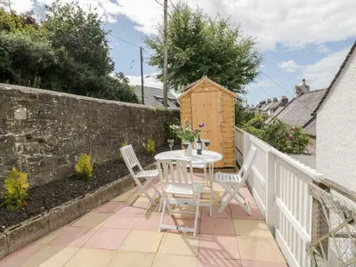 a patio with a table and chairs on a balcony at Haven Cottage in Kirkcudbright