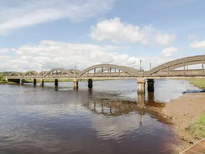 a bridge over a river with some water and clouds at Haven Cottage in Kirkcudbright