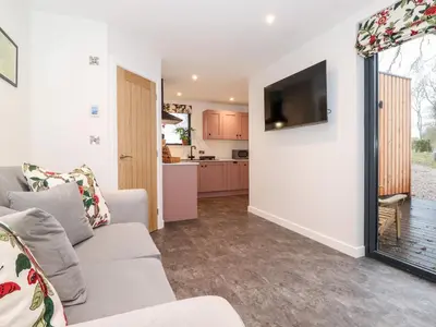 a living room with a couch and a tv on a wall at Herdwick Cabin in Penrith