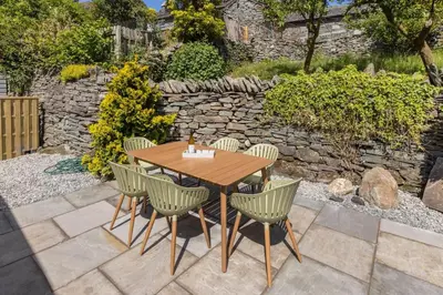 a wooden table with chairs and a stone wall at Langdale Boulders, Ambleside, Fantastic views in Chapel Stile