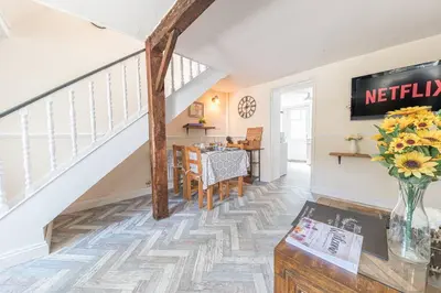 a living room with a staircase and a table at Charming Cottage, Lake District in Little Broughton
