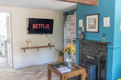 a living room with a fireplace and a tv on the wall at Charming Cottage, Lake District in Little Broughton