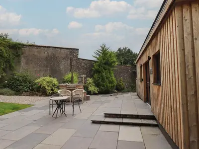 a patio with chairs and a table next to a building at The Gardener's Retreat in Penrith