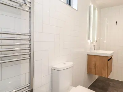 a white bathroom with a toilet and a sink at The Gardener's Retreat in Penrith
