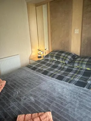 a bedroom with two beds with plaid sheets at Bay 1 in Kirkcolm
