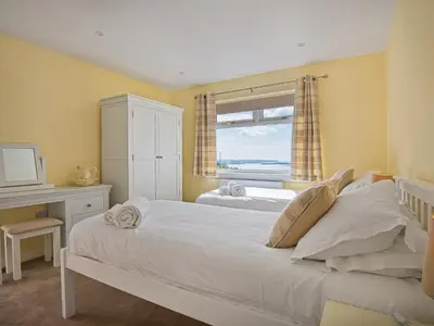 a bedroom with two beds and a desk and a window at High Auchenlarie Cottage in Carsluith