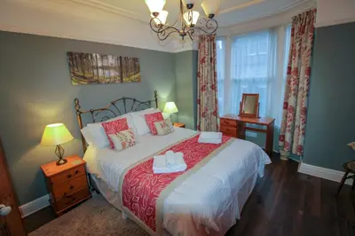 a bedroom with a large bed and a chandelier at Carlton Cottage all ground floor, centrally located in Keswick in Keswick