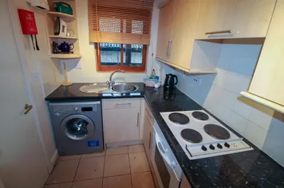 a small kitchen with a sink and a washing machine at Glenmore, Hewetson Court, centrally located 1st floor apartment in Keswick in Keswick