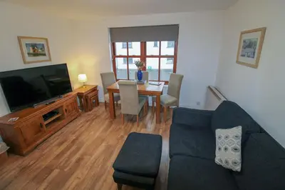 a living room with a couch and a table and a television at Glenmore, Hewetson Court, centrally located 1st floor apartment in Keswick in Keswick