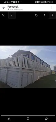 a white building with a fence in the grass at Birds Eye View in Mainsriddle