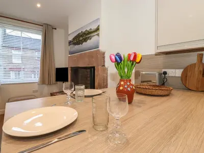 a table with plates and glasses and a vase of flowers at Jack's Cottage in Keswick