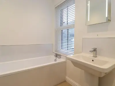 a white bathroom with a sink and a bath tub and a window at Jack's Cottage in Keswick