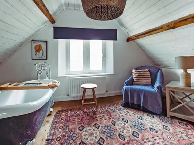 a attic bathroom with a tub and a chair at Top Lodge in Carlisle