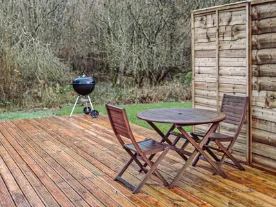 a barbecue grill and a table and chairs on a deck at Top Lodge in Carlisle