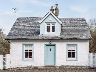 a white house with a blue door and a fence at Top Lodge in Carlisle